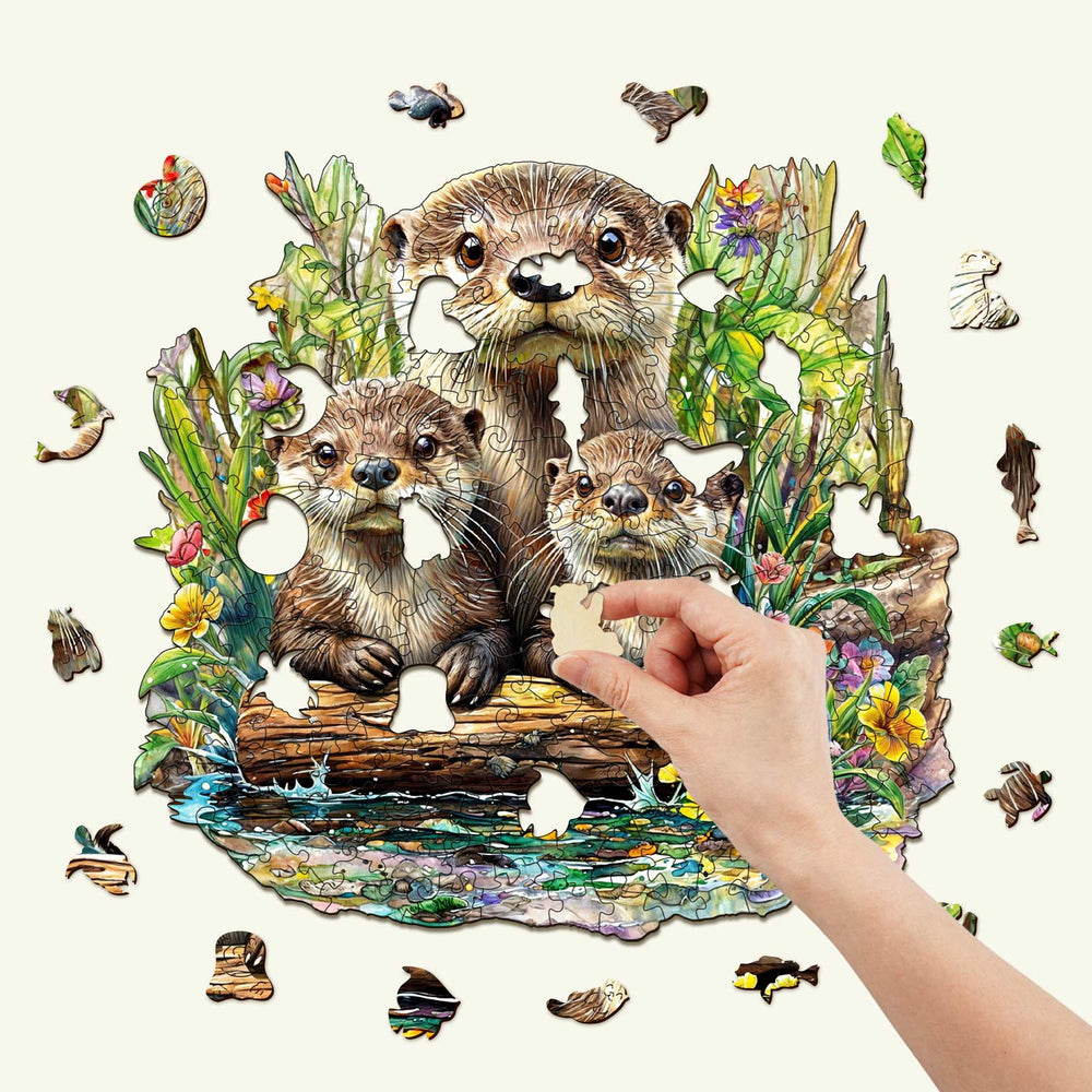 Hand completing an Otter Wooden Jigsaw Puzzle with playful otter artwork and vibrant nature background.