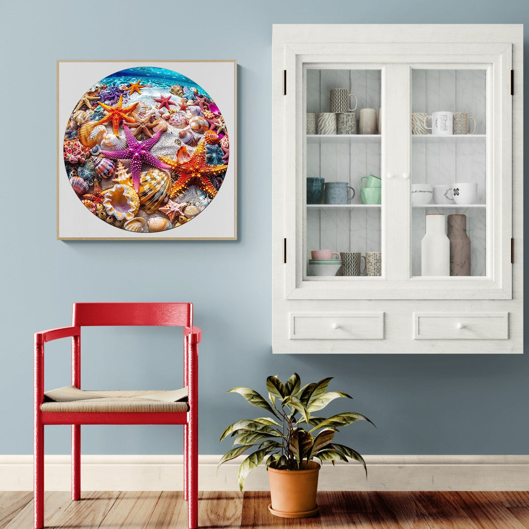Colorful starfish and seashells artwork displayed on a wall by a red chair and glass cabinet.