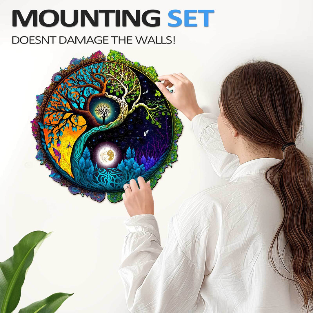 Woman installing a vibrant Yin Yang Tree of Life wall art with a mounting set that doesn't damage walls.