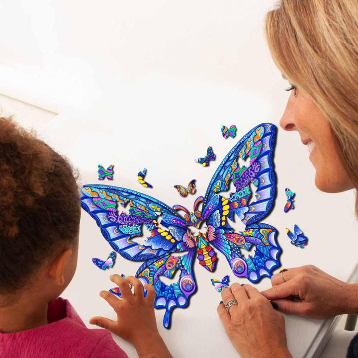 A woman and child assembling a colorful butterfly wooden jigsaw puzzle together on a table.