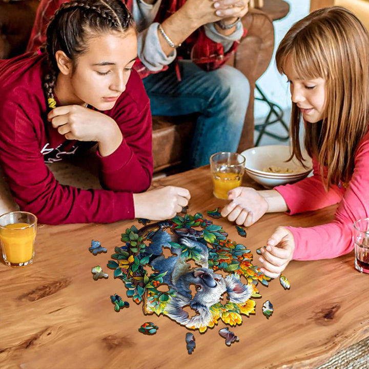 Two children concentrating on assembling a Koala wooden jigsaw puzzle at a wooden table with drinks.